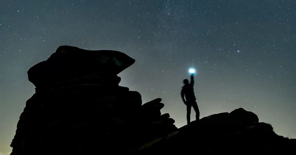 Homem segurando uma lanterna sob o céu noturno.