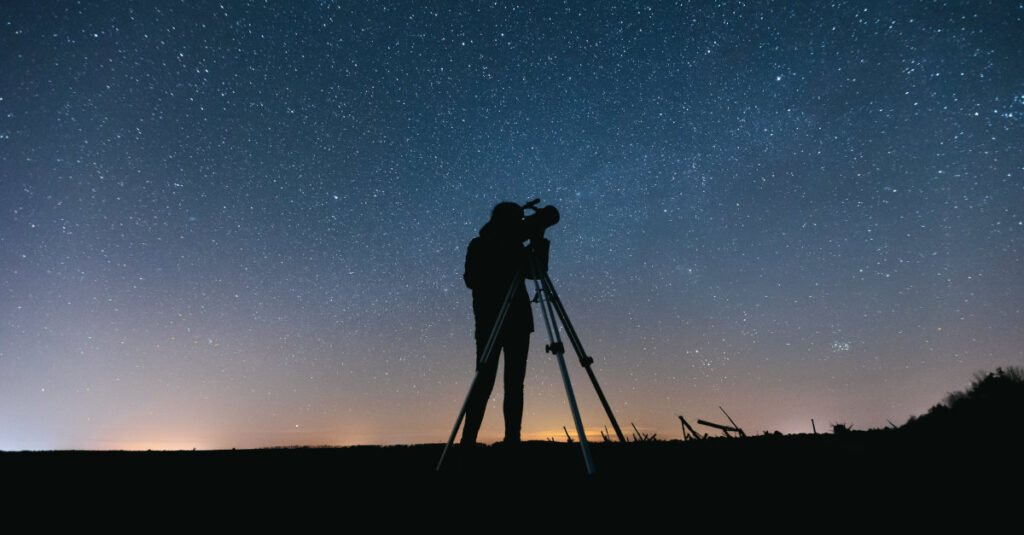Pessoa utiliza um telescópio newtoniano para observar o céu.