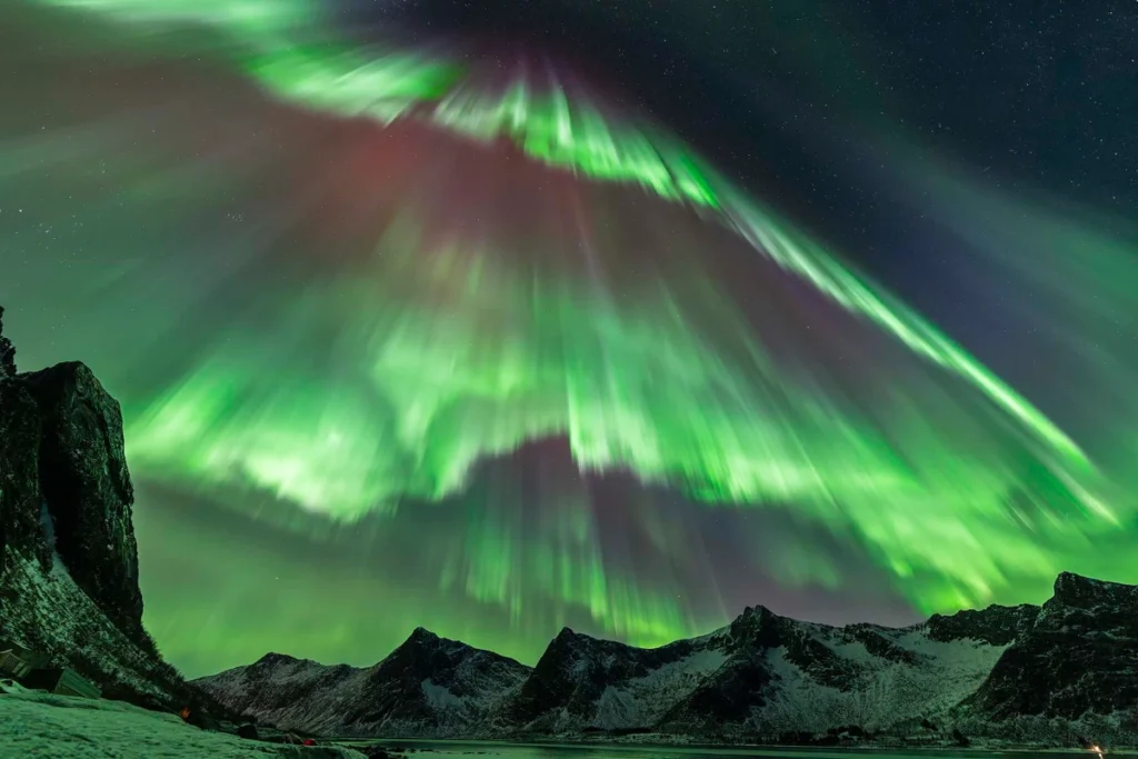 Uma enxurrada auroral © Julien Cadena (França). A câmera havia sido posicionada de frente para os icônicos picos “Dentes do Diabo”, na ilha de Senja, na Noruega. Julien Cadena esperava que a aurora boreal surgisse diretamente acima dos cumes recortados, mas ela acabou se intensificando na direção oposta. Sua intensidade e velocidade eram de tirar o fôlego. Capturada com uma câmera Sony Alpha 7 IV, 14 mm f/2.8, ISO 3200, exposição de 1 segundo. Local: Lyngen, Troms, Noruega, 20 de janeiro de 2026