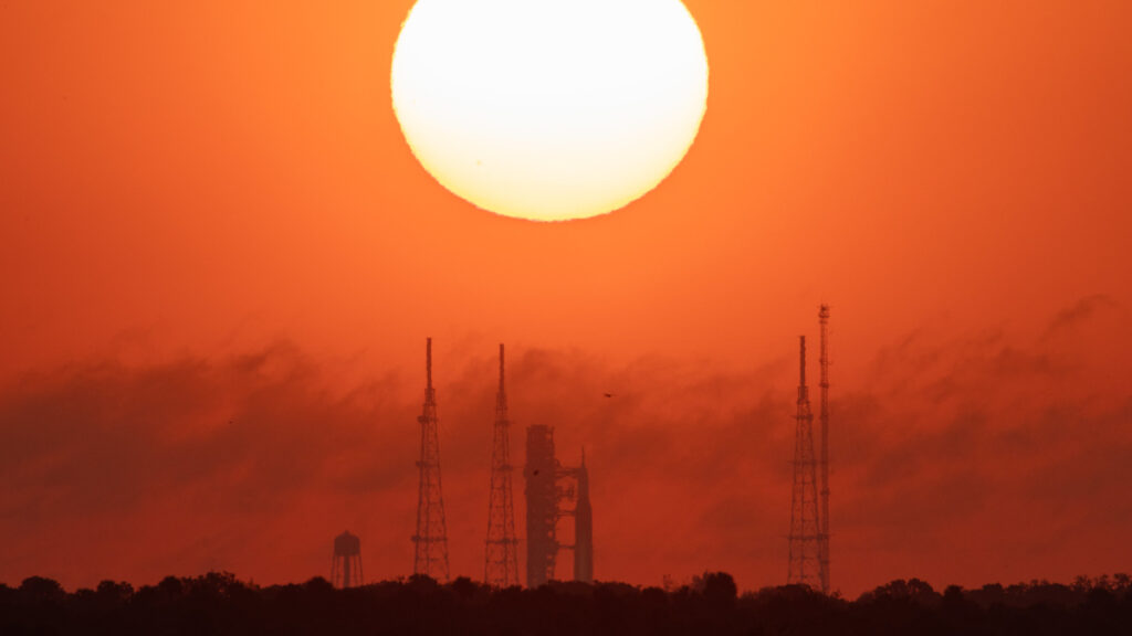 O Sol nascente ilumina o céu no dia 24 de março, enquanto o foguete da Artemis 2 aparece na rampa de lançamento.