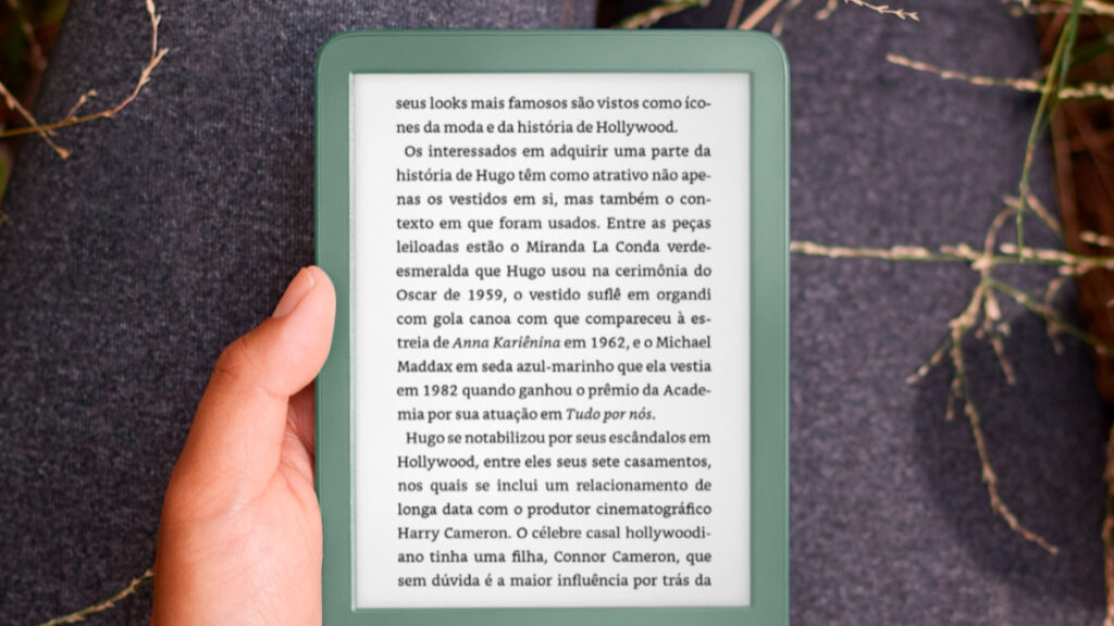 Pessoa segurando kindle em campo.