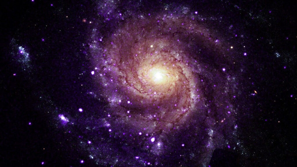 Imagem composta de uma galáxia espiral M101, uma das seis galáxias identificadas que abrigam uma nova classe de objetos misteriosos que emitem raios-X de baixa energia (Crédito: Raio-X: NASA/CXC/Univ. de Alabama/M. Muhibullah et al.; Óptico: NASA/ESA/STScI; Processamento de Imagem: NASA/CXC/SAO/N. - Wolk)
